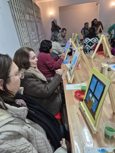 Turma pintando em cavaletes de mesa, com telas de paisagem já começadas