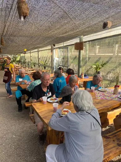 Grupo reunido na mesa comprida da área externa coberta, na hora do café