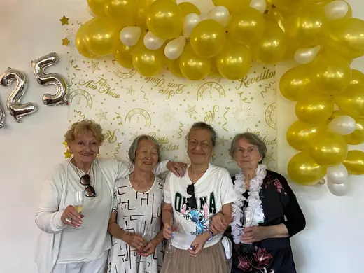 Quatro senhoras diante do painel de balões dourados com o número 25, na festa de réveillon